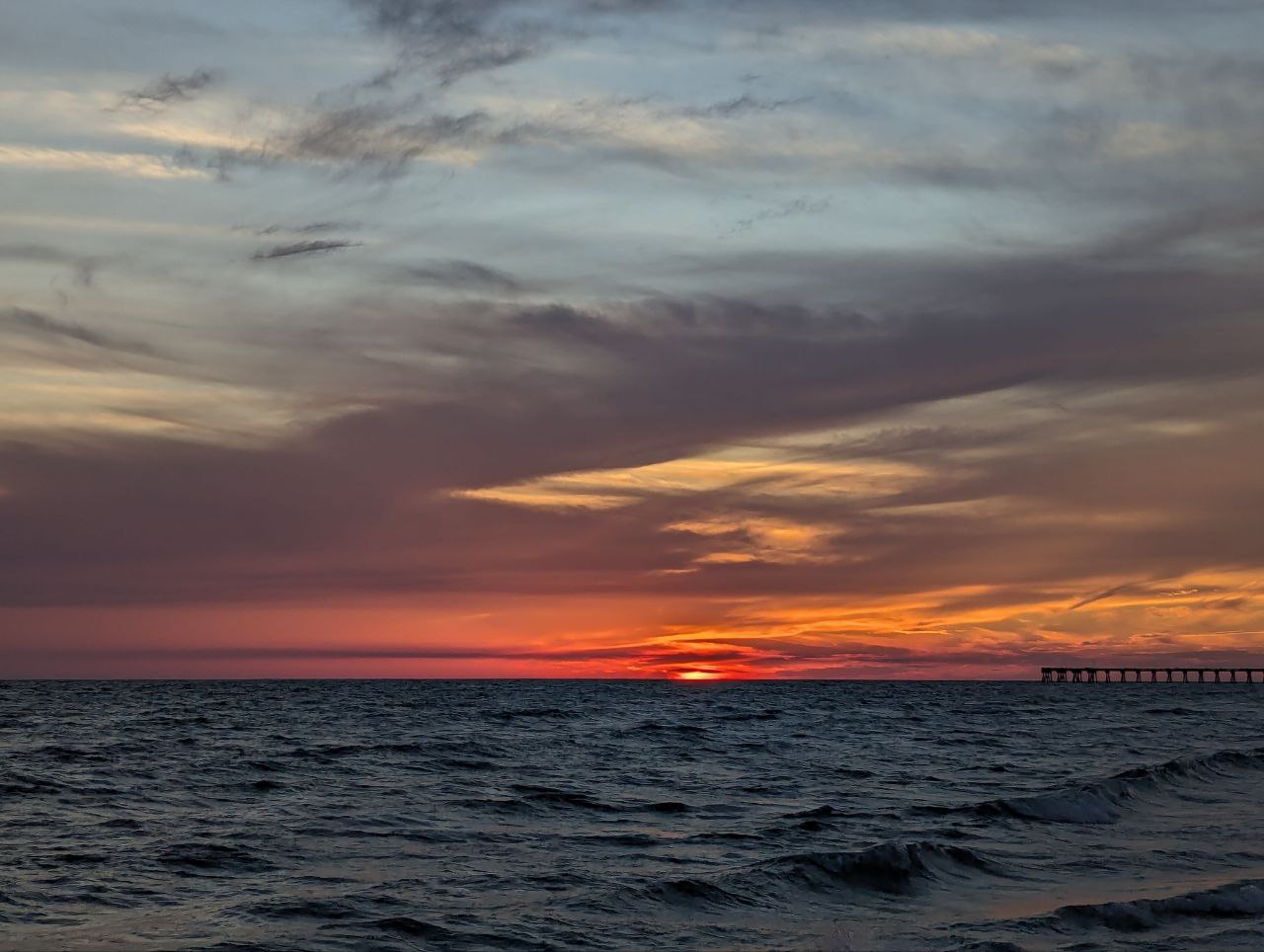The sun, a molten coin, sinks into the ocean's velvet purse, painting the sky with hues of saffron and amethyst.